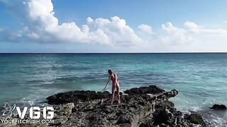 A fit girl is playing with her body on a nudist beach