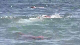 A mature woman goes swimming naked on a sunny beach