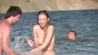 A mature woman goes swimming naked on a sunny beach